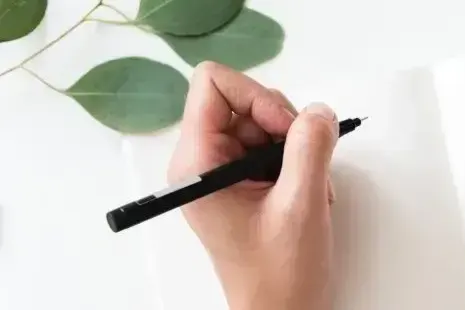 Hand, die mit einem Fineliner auf ein leeres Blatt zeichnet